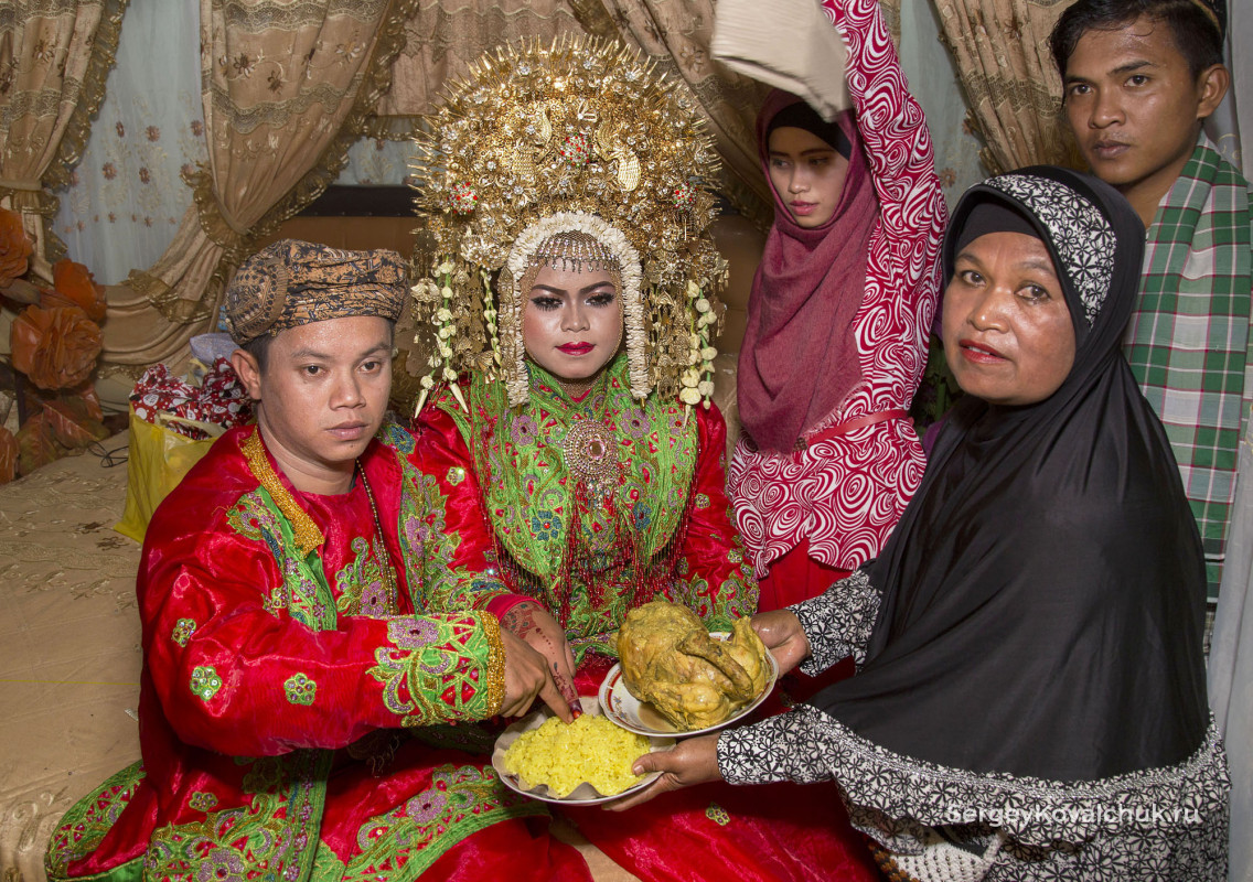 Жених и невеста погружают одновременно указательные пальцы в тарелку с рисом
