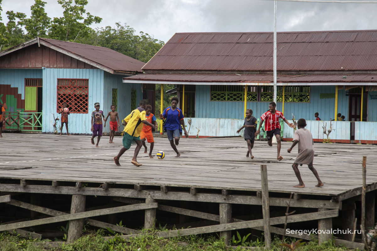 На площадке у школы дети играют в футбол